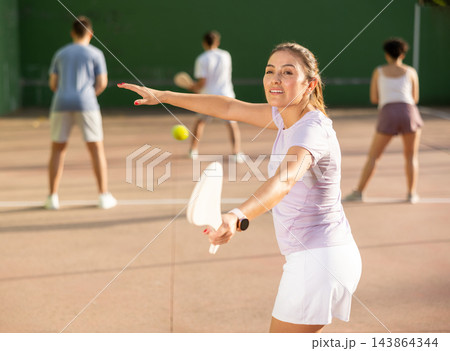 Young Latina playing pelota on open court on summer day 143864344