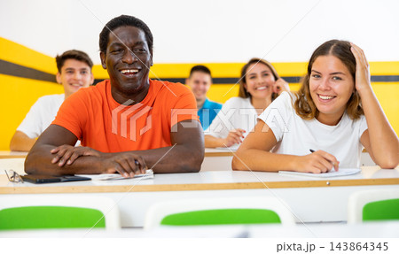 Cheerful smiling adult students at their desks in university classroom 143864345