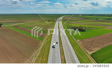 Aerial view of highway crossing green agricultural fields Aerial view of highway crossing green agricultural fields 143865920