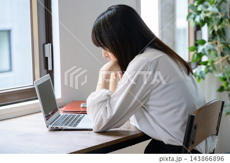 オフィスでノートパソコンを見て悩む日本人女性 143866896
