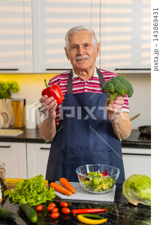 Senior old man showing seasonal vegetables in kitchen explaining healthy diet and nutrition choices 143869431
