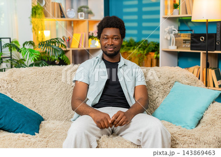 African American young man on home sofa looking at camera with gentle smile in calm portrait scene African American young man on home sofa looking at camera with gentle smile in calm portrait scene 143869463