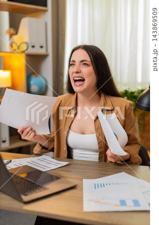 Young woman on home table frustrated by work reports finding mistakes and tossing papers in stress 143869509