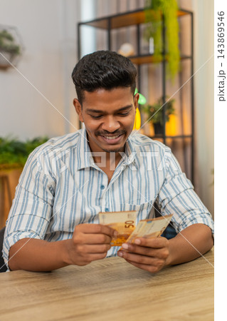 Indian man counts euro cash bonus salary plans invest smiles proud income wealth profit success joy 143869546