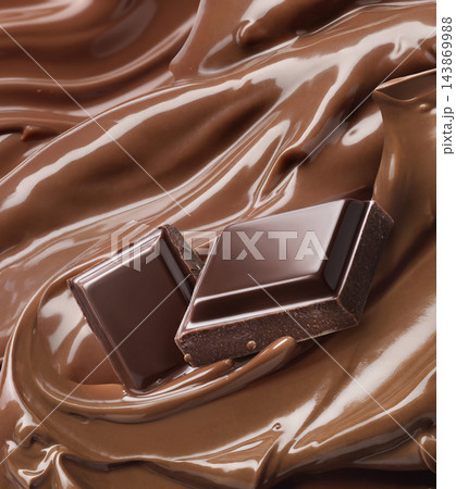 Chocolate pieces on glossy melted cocoa butter swirl Chocolate pieces on glossy melted cocoa butter swirl 143869988