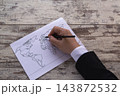 Business Professional Marking A World Map On Paper For Travel Planning And Strategic Mapping 143872532