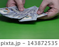 Hands Counting Cash: US Dollar Hundred Bills Money Transaction on Green Background 143872535