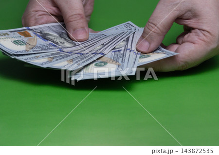 Hands Counting Cash: US Dollar Hundred Bills Money Transaction on Green Background 143872535