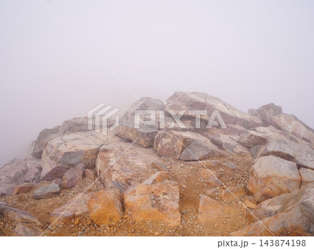 濃霧に霞む岩だらけの山頂 視界不良の登山イメージ 143874198