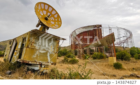 Rusty satellite dish on a wrecked truck in front of the steel frame of an unfinished Soviet solar plant, Armenia Rusty satellite dish on a wrecked truck in front of the steel frame of an unfinished Soviet solar plant, Armenia 143874827
