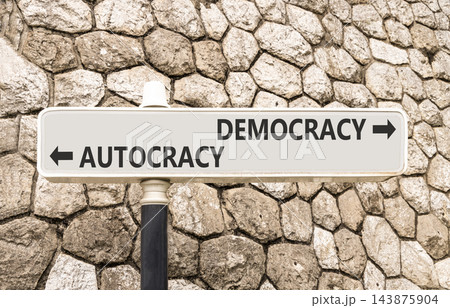 Democracy or autocracy words symbol. Concept words Democracy Autocracy on beautiful white road sign. Beautiful stone wall background. Business democracy autocracy concept. Copy space Democracy or autocracy words symbol. Concept words Democracy Autocracy on beautiful white road sign. Beautiful stone wall background. Business democracy autocracy concept. Copy space 143875904