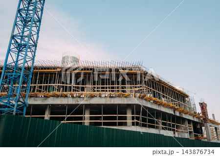 Modern building under construction with tower crane and concrete framework Modern building under construction with tower crane and concrete framework 143876734