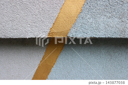 Zigzag formed from a glossy gold stripe on a roughly plastered surface of two slabs 143877038