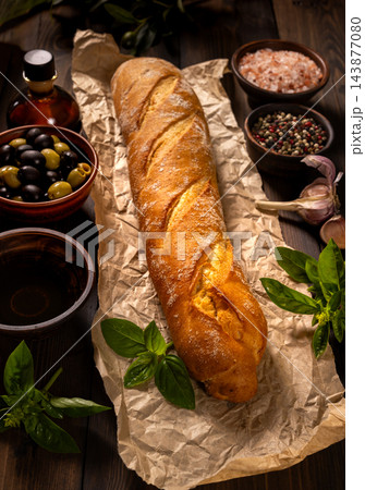 Crusty baguette with olives, herbs and rustic seasoning Crusty baguette with olives, herbs and rustic seasoning 143877080