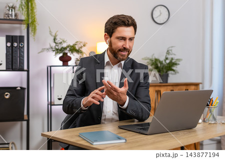 Middle-aged businessman joins laptop video conference wearing earphones talking friendly to team Middle-aged businessman joins laptop video conference wearing earphones talking friendly to team 143877194