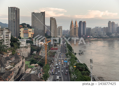 Ornate golden spires dominate the modern riverfront skyline of Chongqing's Nan'an District. This high-angle view perfectly illustrates the dramatic contrast between architectural elegance and active 143877425