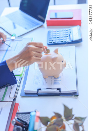 Businessman saving money into piggy bank for retirement and emergency fund. 143877782