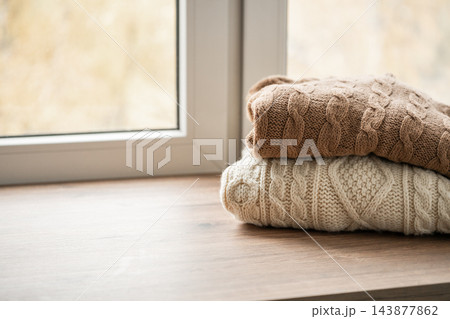 Cozy knitted sweaters on windowsill with copy space 143877862