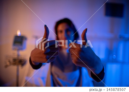 Patient shows confident positive attitude. Smiling individual exhibiting hope and recovery signs. Person with cheerful expression giving thumbs up in healthcare setting Patient shows confident positive attitude. Smiling individual exhibiting hope and recovery signs. Person with cheerful expression giving thumbs up in healthcare setting 143878507