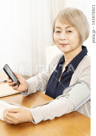 リビングで血圧を測り笑顔のシニア女性 143878921