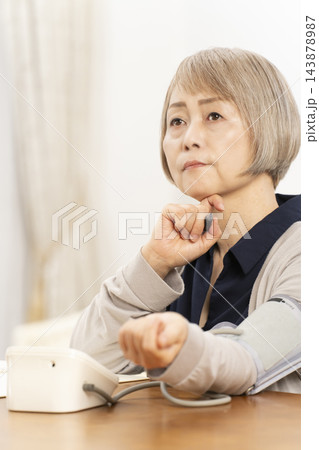 リビングで血圧を測り落ち込むシニア女性 143878987