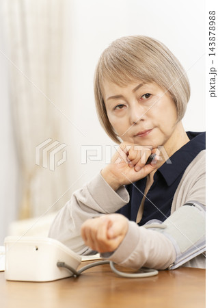 リビングで血圧を測り落ち込むシニア女性 143878988