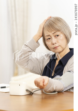 リビングで血圧を測り落ち込むシニア女性 143878997