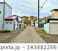 住宅地の建物と車庫に挟まれた細い舗装道路 143882266