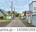 車庫と電柱が並ぶ住宅地の細い舗装道路 143882268