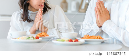 食卓のパスタを前に手を合わせる夫婦の手元。 食卓のパスタを前に手を合わせる夫婦の手元。 143887345