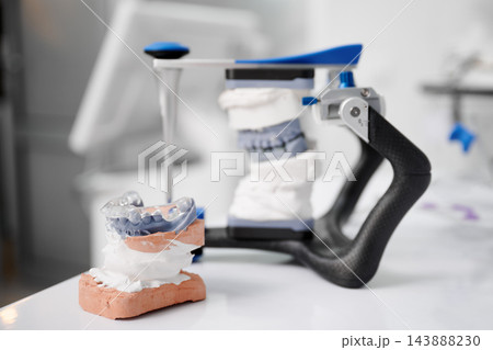 Dental articulator with jaw casts and occlusal splint. Close up of gnathological treatment Dental articulator with jaw casts and occlusal splint. Close up of gnathological treatment 143888230
