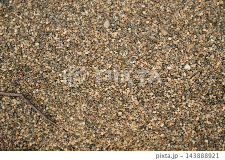 High angle close up shot of a uniform coarse sand texture mixed with fine gravel and tiny pebbles under direct daylight 143888921