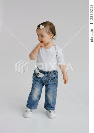 Toddler Girl in Denim Jeans Standing in Studio Toddler Girl in Denim Jeans Standing in Studio 143889218