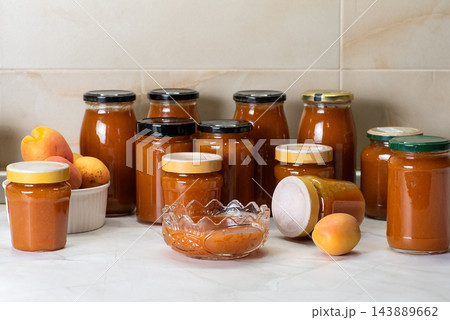 Assorted jars of apricot jam on a kitchen countertop 143889662