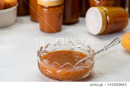 Homemade apricot jam in a glass dish with jars in the background 143889663