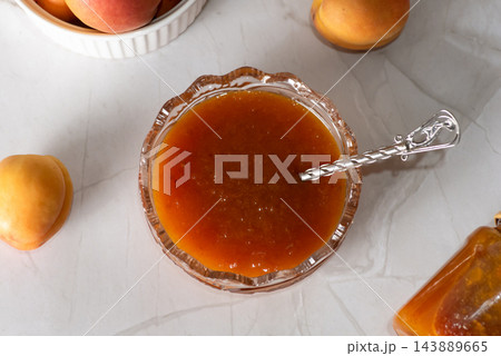 Homemade apricot jam in a glass bowl with a silver spoon 143889665