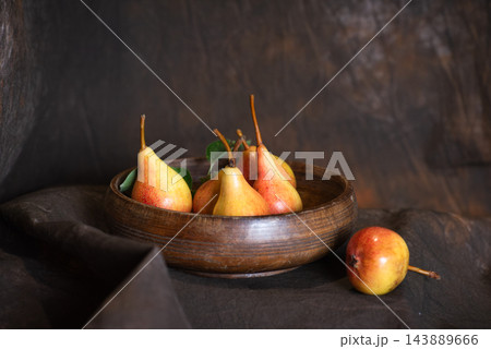 Fresh pears in a wooden bowl on a textured brown background Fresh pears in a wooden bowl on a textured brown background 143889666