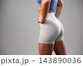 Fit woman in gray high-waisted athletic shorts and blue sports top standing confidently 143890036