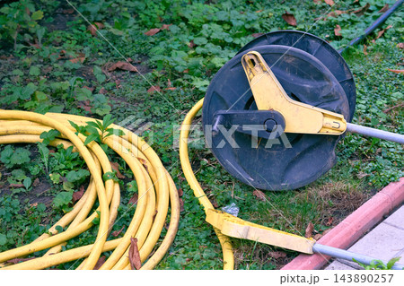 Summer irrigation.Watering rubber hose reel lying on grass Summer irrigation.Watering rubber hose reel lying on grass 143890257