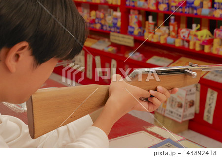 縁日の射的を楽しむ子ども 143892418