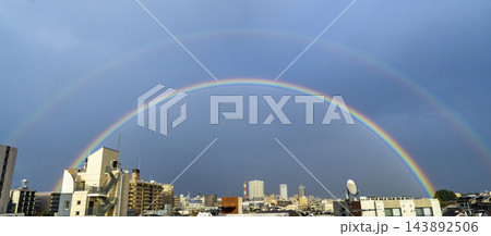 夕方の雨上がり、都心の街並みの上空に大きく架かる二重の虹 143892506