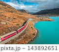 Aerial view of red train near alpine mountain lake and cloudy sky 143892651