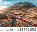 Aerial view of red train is moving through bridges in swiss alps 143892652