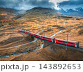 Aerial view of red train is moving through bridges in mountains 143892653