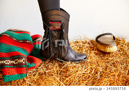 female black boot on stable straw bale 143893738