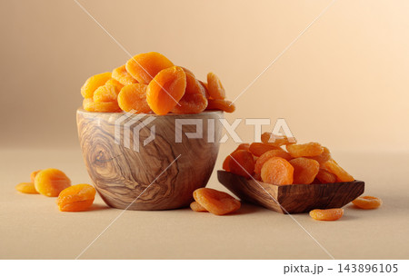 Organic dried apricots in wooden bowl on a beige background. Organic dried apricots in wooden bowl on a beige background. 143896105