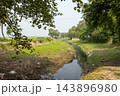 Narrow rural water canal flowing through green fields and trees. Scenic countryside stream landscape in a calm outdoor environment. Narrow rural water canal flowing through green fields and trees. Scenic countryside stream landscape in a calm outdoor environment. 143896980
