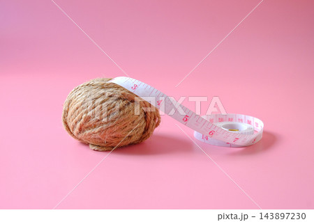 A coil of jute rope with measuring tape on background. 143897230