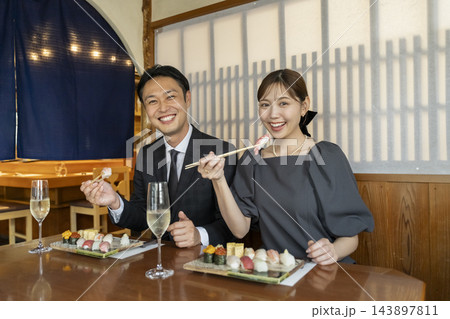 お寿司を食べる笑顔のアラフォーの男女　カメラ目線 143897811