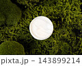 Top view of open cosmetic jar with white cream on lush green natural moss background 143899214